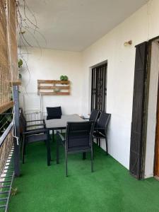 Apartamento en el centro de Miami Platja 155B - INMO22 في هوسبيتاليت دي لانفنت: طاولة وكراسي في غرفة ذات أرضية خضراء