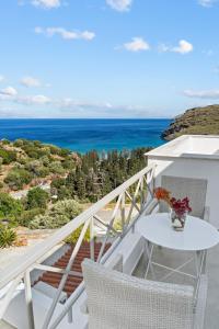 einen weißen Tisch und Stühle auf einem Balkon mit Meerblick in der Unterkunft Seaside & Modern Flats near Chora in Steniaí