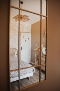 een spiegel die een slaapkamer met een bed en een deur reflecteert bij « La Casa Normande » entre Ville & Plages in Esquay-sur-Seulles