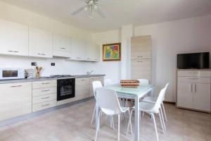una cocina con mesa y sillas blancas. en GARDASUN 2 Lovely flat Lake close Pet friendly, en Padenghe sul Garda