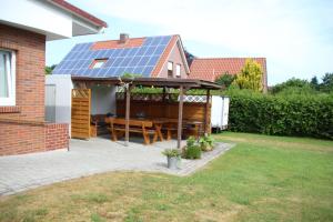 a patio with a table with a solar roof at Ferienwohnung Drieling_ 85091 in Ostrhauderfehn