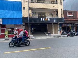un grupo de personas montando una motocicleta calle abajo en Penginapan Star Ambon Mitra RedDoorz, en Ambon