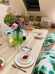 a table with plates and flowers in a living room at Alte Scheune, Parken-WLAN-Küche-Bad-Tierlieb in Däniken