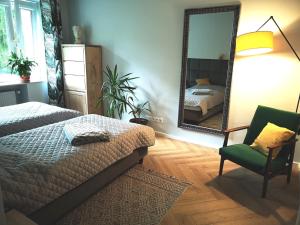 a bedroom with a bed and a mirror and a chair at Apartament Nałęczowski Zakątek in Nałęczów