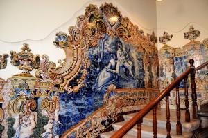 un escalier décoré dans une pièce avec un mur recouvert de peintures dans l'établissement Coimbra Portagem Hostel, à Coimbra