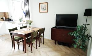 comedor con mesa con sillas y TV en Apartament Nałęczowski Zakątek en Nałęczów