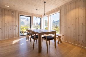 a dining room with a table and chairs and windows at The Panorama - Sørvågen Lofoten in Sørvågen