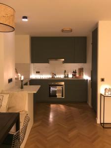 a kitchen with dark green cabinets and a wooden floor at LuxeLevallois chic stay with balcony 800 meters from Paris in Levallois-Perret +24 photos