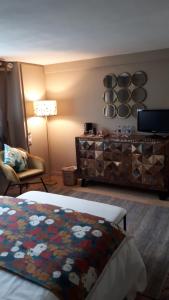 a bedroom with a bed and a dresser at Chambre d'hôtes Les Hortensias in Gelos