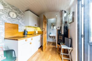 a kitchen with white cabinets and a clock on the wall at The Little John Petite Cosy log Cabin Romantic Stay Sleeps 2 Near Sherwood Forest at Fairview Farm Nottingham set in 88 acres in Blidworth