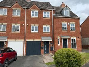 una casa de ladrillo con un coche aparcado delante de ella en Three Bed Townhouse with Parking en Telford