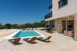 a swimming pool with chairs and a house at Villa Kate ZadarVillas in Knežević