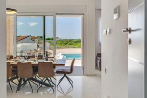 a dining room with a table and chairs and a pool at Villa Kate ZadarVillas in Knežević