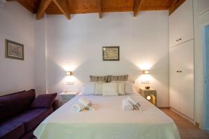 a bedroom with a large white bed and a couch at Bibelo Holiday Home in Laganas