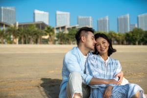 Un uomo e una donna seduti sulla spiaggia di Renaissance Xiamen Hotel a Xiamen
