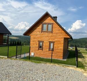 ein Holzhaus mit einem Zaun davor in der Unterkunft Domki w Bieszczadach Nowa Zelandia in Berezka