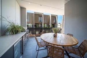 a kitchen with a wooden table and chairs on a balcony at SYLO Luxury Apartments - 1Gb Fibre Internet in Adelaide