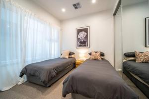 a bedroom with two beds and a window at SYLO Luxury Apartments - 1Gb Fibre Internet in Adelaide