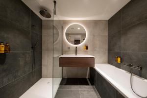 a bathroom with a tub and a sink and a mirror at Bilderberg Europa Hotel Scheveningen in Scheveningen