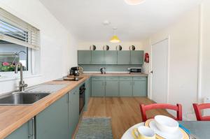 a kitchen with blue cabinets and a sink and a table at Cottage 446 - Letterfrack in Letterfrack