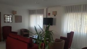 una sala de estar con sillas rojas y una mesa con una planta en Hotel Punta Seame, en Portonovo