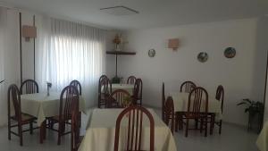 una sala da pranzo con tavoli bianchi e sedie in legno di Hotel Punta Seame a Portonovo