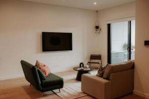 ein Wohnzimmer mit einem Sofa und einem TV an der Wand in der Unterkunft SYLO Luxury Apartments - LVL 2 in Adelaide