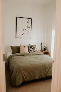ein Schlafzimmer mit einem Bett und einem Bild an der Wand in der Unterkunft SYLO Luxury Apartments - LVL 2 in Adelaide