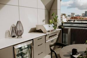 une cuisine avec une cuisinière et une table sur un balcon dans l'établissement SYLO Luxury Apartments - Penthouse LVL 3, à Adélaïde