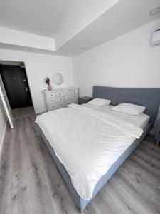 a white bedroom with a large white bed with white sheets at Cosmopolis Bliss: Your Home Away from Home in Ştefăneştii de Jos
