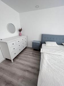 a bedroom with a bed and a dresser and a mirror at Cosmopolis Bliss: Your Home Away from Home in Ştefăneştii de Jos