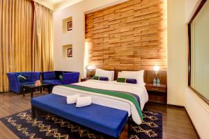 a hotel room with a large bed and blue chairs at Sunday Hotel Jaipur in Jaipur