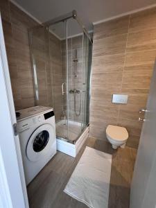 a bathroom with a washing machine and a shower at Cosmopolis Bliss: Your Home Away from Home in Ştefăneştii de Jos