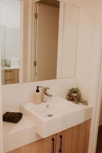 La salle de bains est pourvue d'un lavabo blanc et d'un miroir. dans l'établissement SYLO Luxury Apartments - Penthouse LVL 3, à Adélaïde