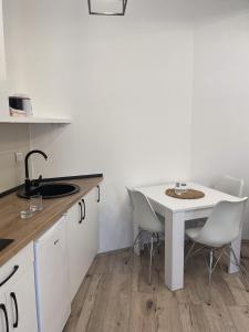 uma cozinha com uma mesa branca e cadeiras em Hexagon Apartment em Temerin