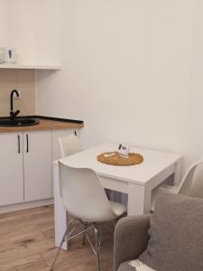 uma cozinha com uma mesa branca e cadeiras num quarto em Hexagon Apartment em Temerin