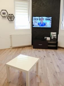 ein Wohnzimmer mit einem weißen Tisch und einem TV in der Unterkunft Hexagon Apartment in Temerin