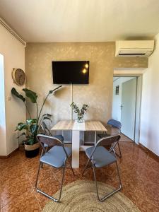a room with a table with chairs and a tv on the wall at Apartments Dent in Umag