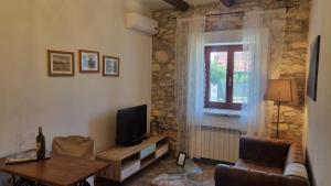 salon z kanapą, telewizorem i oknem w obiekcie Rooms & Apartment STELIO w mieście Loborika