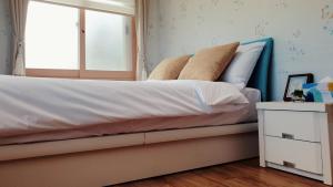 ein Bett mit weißer Bettwäsche und Kissen sowie einem Fenster in der Unterkunft Jeju Mermuri in Seogwipo
