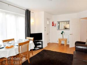un salon avec une table à manger et une télévision dans l'établissement Admiral's Quarter Apartment 5, à Weymouth