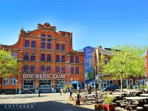 un grand bâtiment en briques avec des tables devant lui dans l'établissement Admiral's Quarter Apartment 5, à Weymouth