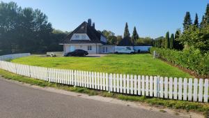 a white picket fence in front of a house at FEWO Weissenhäuser Strand in Wasbuck