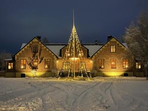 une grande maison avec un arbre de Noël dans la neige dans l'établissement Almaån Bed and Breakfast, à Vankiva