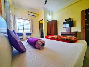 a bedroom with two beds with purple and red pillows at STAYMAKER Hotel QInn in Kushālnagar