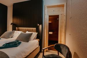 1 dormitorio con 1 cama y 1 silla junto a una puerta en Residence Oude Haven luxe appartementen met sauna, en Colijnsplaat