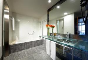 a bathroom with a sink and a tub and a mirror at Eurostars Las Salinas in Caleta De Fuste