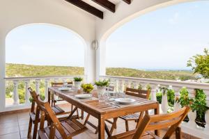 uma sala de jantar com uma mesa e cadeiras numa varanda em Villa Cala Llonga em Maó