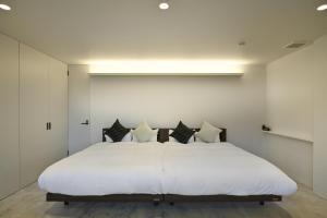 a bedroom with a large white bed with black pillows at Mont-モン-KAMOGAWA STAY and HOTEL in Kyoto