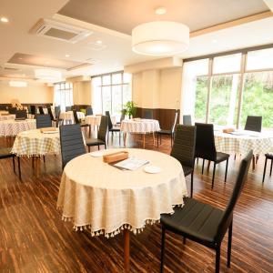 uma sala de jantar com mesas, cadeiras e janelas em 阪南国际HOTEL em Hannan